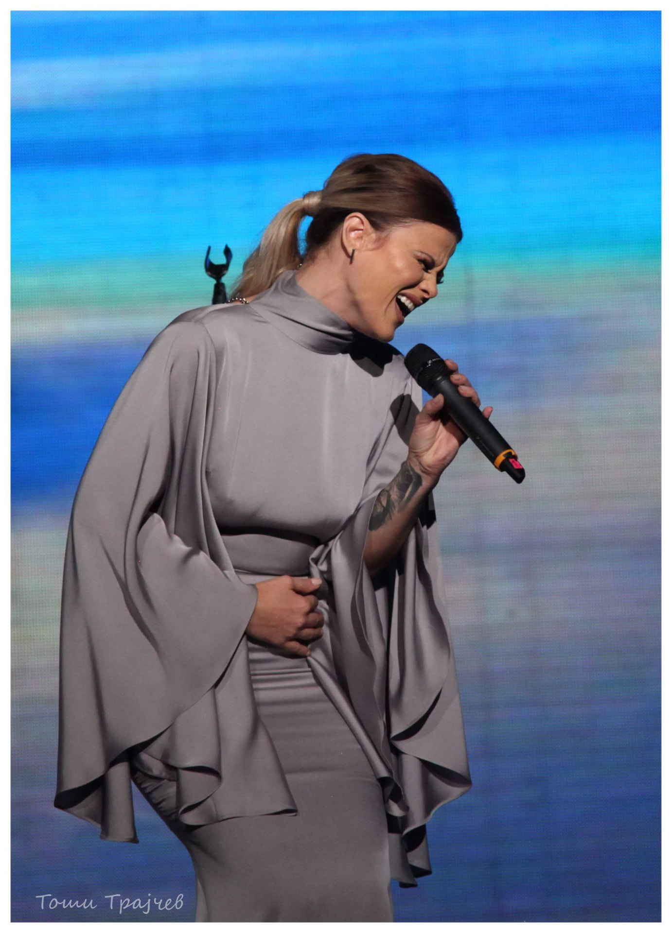 Dani Dimitrovska performing in a grey cape dress
